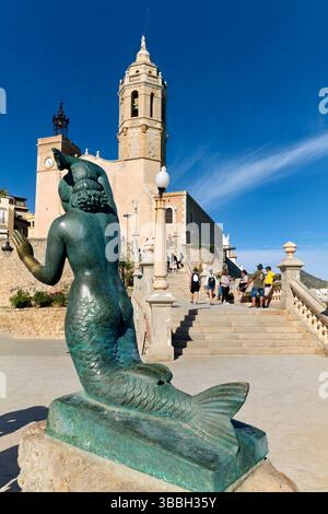 Sitges Spanien Kirche mit Blick auf das Mittelmeer mit Menschen, die entlang der Promenade spazieren gehen Stockfoto