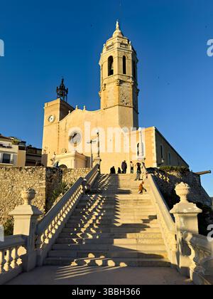 Sitges Spanien Kirche mit Blick auf das Mittelmeer mit Menschen, die entlang der Promenade spazieren gehen Stockfoto