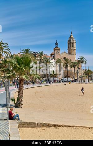 Sitges Spanien Kirche mit Blick auf das Mittelmeer mit Menschen, die entlang der Promenade spazieren gehen Stockfoto