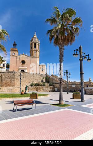 Sitges Spanien Kirche mit Blick auf das Mittelmeer mit Menschen, die entlang der Promenade spazieren gehen Stockfoto