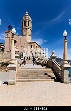 Sitges Spanien Kirche mit Blick auf das Mittelmeer mit Menschen, die entlang der Promenade spazieren gehen Stockfoto