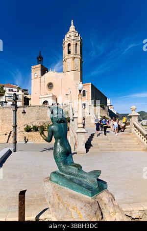 Sitges Spanien Kirche mit Blick auf das Mittelmeer mit Menschen, die entlang der Promenade spazieren gehen Stockfoto
