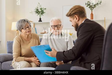 Seniorenpaar im Gespräch mit Finanzagenten über Krankenversicherung im Ruhestand zu Hause. Stockfoto