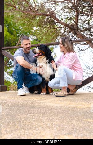 Kaukasisches Paar mit Hund, der draußen posiert und während des Urlaubs am Strand lächelt Stockfoto