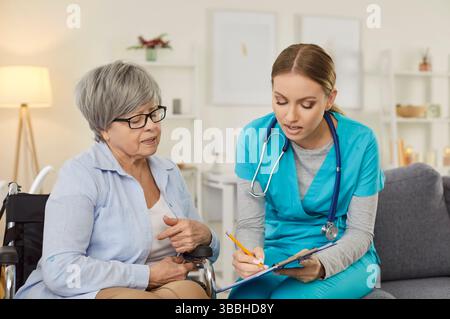 Krankenschwester zeigt medizinische Testergebnisse für behinderte weibliche Patientin im Rollstuhl in der medizinischen Klinik Stockfoto