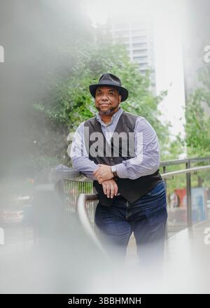Ein dunkelhäutiger Mann, der draußen im Regen einen Hut trägt Stockfoto