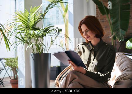 Beschäftigte, glückliche junge Geschäftsfrau, die im Büro ein Notizbuch hält. Stockfoto