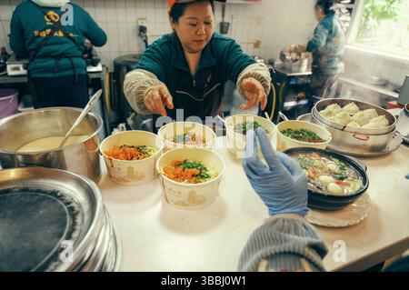 Der Koch serviert Tomatennudelschalen und dampfende Knödel in einem Snackladen in der Changsha Street Stockfoto