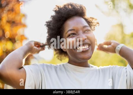 Lächelnde junge Frau im Park an einem sonnigen Tag Stockfoto