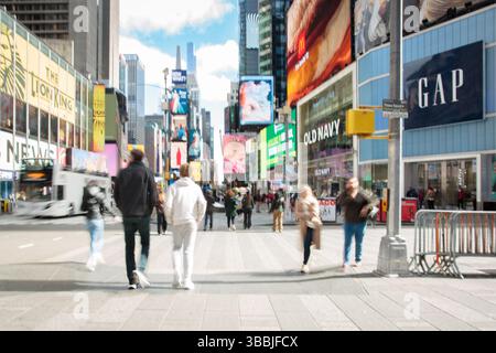 Verschwommene Menschen, die an einem frühen Frühlingsmorgen am Time Square in New York City spazieren gehen Stockfoto