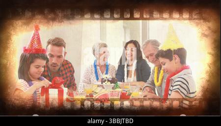 Familienmitglieder aus mehreren Generationen, die im Speisesaal Geburtstag feiern, mit Kuchen und Geschenken Stockfoto
