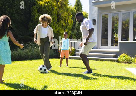 Auf dem Hinterhof vor dem modernen grauen Haus spielen verschiedene Familien Fußball spielen Stockfoto
