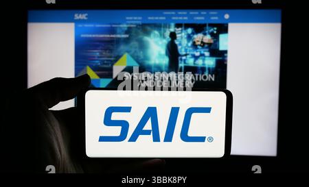 Stuttgart, Deutschland - 01-07-2024: Person mit Mobiltelefon mit Logo der Science Applications International Corporation (SAIC) auf dem Bildschirm Stockfoto