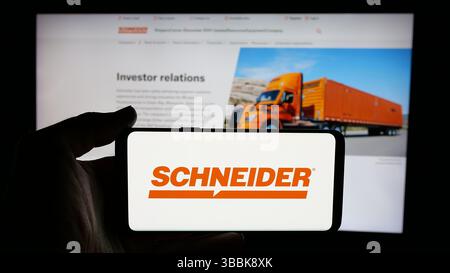Stuttgart, Deutschland - 01-07-2024: Person mit Mobiltelefon mit Logo des US-amerikanischen Logistikunternehmens Schneider National Inc. Auf dem Bildschirm Stockfoto