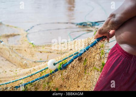 Der halbe Körper eines nicht identifizierten Fischers, der ein Fischernetz zieht. Fisch und Meeresfrüchte, Hobby. Brasilien Stockfoto