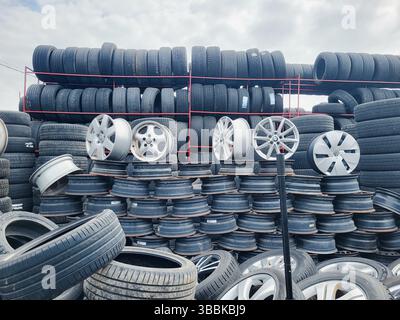 Vilnius, Litauen - 08-05-2025 - Wand aus gebrauchtem Gummi, alten Leichtmetallrädern und aufgestapelten Reifen in einem Reifenwartungsbereich eines Autoteilemarktes Stockfoto