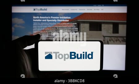 Stuttgart, Deutschland - 15.01.2025: Person mit Handy mit Logo des US-amerikanischen Baustoffunternehmens TopBuild Corp. Auf dem Bildschirm Stockfoto