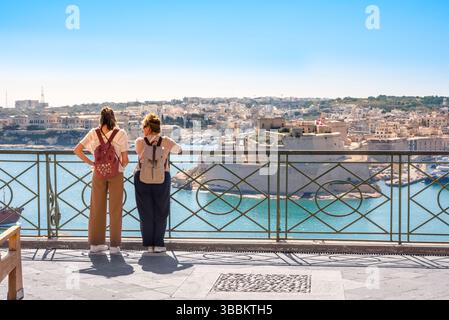 Reisefreundinnen, Rückansicht zweier weiblicher Reisenden, die über den Grand Harbour in Valletta, Malta, blicken Stockfoto