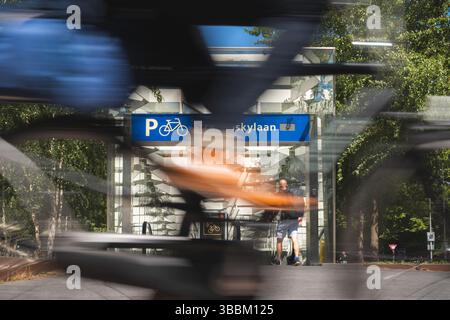 Amsterdam, Niederlande. Mai 2025. Ein Radfahrer fährt an einem Eingang zu einer Tiefgarage für Fahrräder in der Nähe einer U-Bahn-Station vorbei (Wischeffekt aufgrund langer Exposition). Quelle: David Breidert/dpa/Alamy Live News Stockfoto