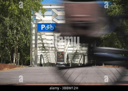 Amsterdam, Niederlande. Mai 2025. Ein Radfahrer fährt an einem Eingang zu einer Tiefgarage für Fahrräder in der Nähe einer U-Bahn-Station vorbei (Wischeffekt aufgrund langer Exposition). Quelle: David Breidert/dpa/Alamy Live News Stockfoto