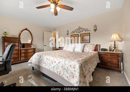 Ein gemütliches Schlafzimmer mit einem komfortablen Bett, einer stilvollen Kommode, einem praktischen Nachttisch, einem modernen Fernseher und einem erfrischenden Deckenventilator Stockfoto