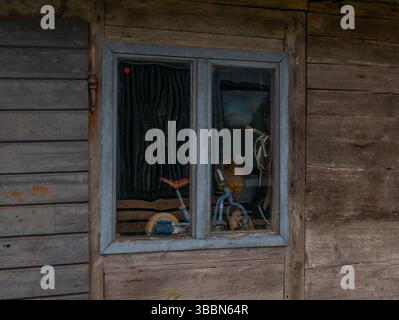 Rustikale Holzwand mit Vintage-Fenster und Fahrradspiegelung. Landschaft, Nostalgie und Vintage-Design-Konzept. Stockfoto