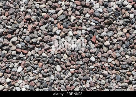 Kiesstein Textur Hintergrund. Kleine zerquetschte Steine aus der Nähe. Natürliche mehrfarbige Kieselsteine. Raue Außenoberfläche. Konstruktionsmaterialmuster. Stockfoto