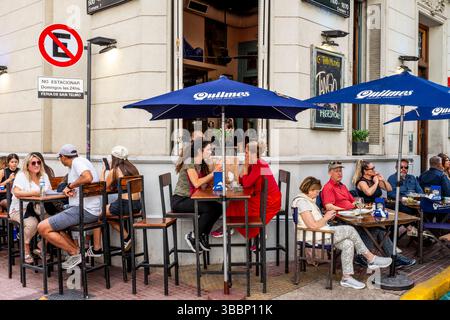 Leute, die während des San Telmo Sunday Market, San Telmo District, Buenos Aires, Argentinien, vor Einem Café/Bar in der Plaza Dorrego sitzen. Stockfoto