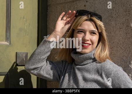 Modische junge Frau passt ihre Sonnenbrille an und genießt einen sonnigen Tag im Freien Stockfoto