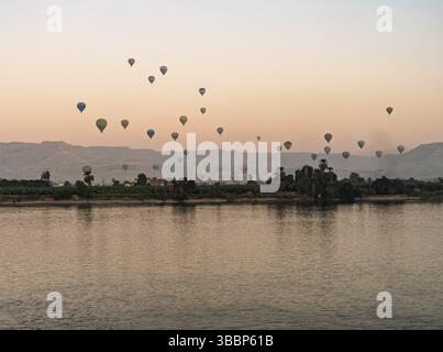 Viele Ballons am Himmel über dem Nil in Luxor für einen Flug bei Sonnenuntergang über dem Tal der Könige Stockfoto