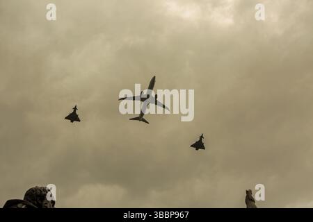 Größeres kommerzielles Flugzeug flankiert von zwei Kampfflugzeugen in einer Fliegerfliege über London am VE Day Stockfoto