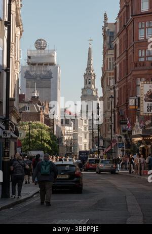 London, Großbritannien - 13. Mai 2025 - Eine Menschenmenge und Touristen spazieren auf der St. Martin's Lane mit Blick auf St. Martin-in-the-Fields und die antike Bu Stockfoto