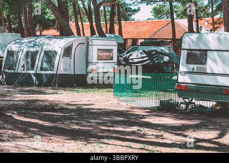 Geparkte Wohnwagen und Zelte, eingebettet zwischen den Bäumen, schaffen eine ruhige Atmosphäre Stockfoto