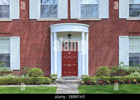 Vor dem traditionellen zweistöckigen Backsteinhaus mit weißen Fensterläden Stockfoto