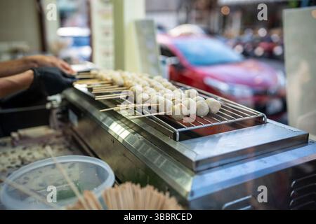 Kochen Sie Flips Schweinefleisch Satay Sticks und gedämpfte Fleischbällchen am Straßencafé in thailand Stockfoto