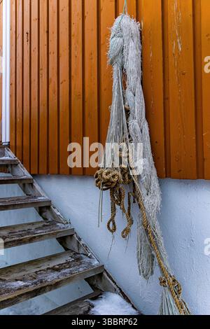 Alte Fischernetze hängen an farbigen Holzwänden der traditionellen Fischerhütte in Norwegen Stockfoto