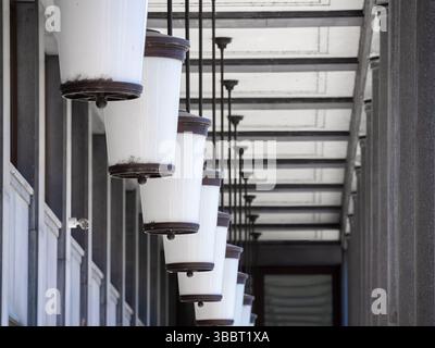 Eine Reihe von hängenden weißen und braunen Leuchten in einer modernen architektonischen Umgebung, die ein klares und minimalistisches Design bieten. Stockfoto