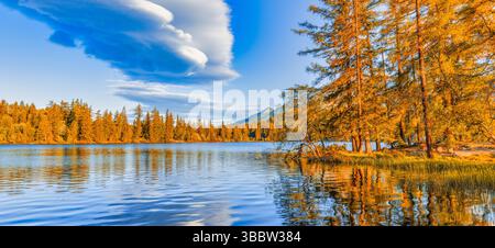 Fantastische Bergherbstsee-Landschaft schöne Kiefern farbenfroher Himmel und Wolken schaffen malerische saisonale Landschaft malerische Wandkunst Hintergrund Stockfoto