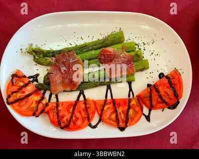 Gegrillter grüner Spargel mit Schinken und Tomatensalat. Spanien. Stockfoto