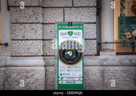 TRIEST, ITALIEN – 17. DEZEMBER 2024: Der an der Wand montierte DAE/AED-Schrank ermöglicht den öffentlichen Zugang zu automatisierten externen Defibrillatoren mit zweisprachiger Beschilderung Stockfoto