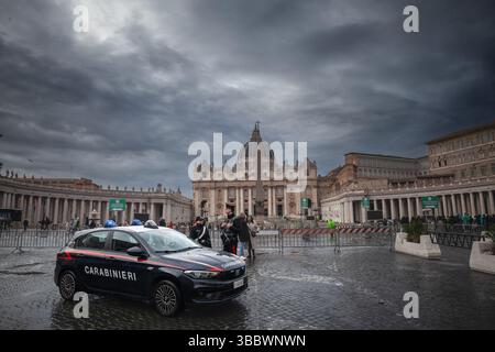 VATIKAN - 15. JANUAR 2025: Carabinieri-Offiziere mit einem Auto auf dem Petersplatz, während Touristen in der Warteschlange im Petersdom stehen. Carabinieri sind Polizisten Stockfoto