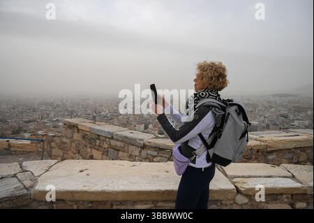 Athen, Griechenland, 16. Mai 2025. Ein Besucher macht Fotos, während Athen mit Staubwolken bedeckt ist. Eine dicke Decke aus Sahara-Staub fegte am Freitag über die griechische Hauptstadt und ließ die Stadt trüben und warnte die Behörden. Quelle: Dimitris Aspiotis/Alamy Live News Stockfoto
