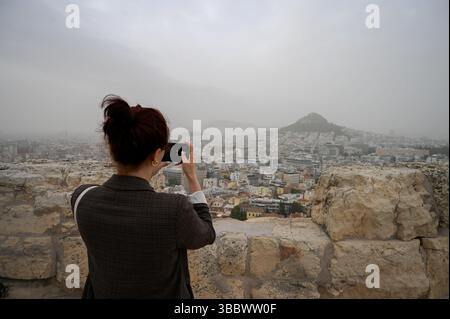 Athen, Griechenland, 16. Mai 2025. Ein Besucher macht Fotos, während Athen mit Staubwolken bedeckt ist. Eine dicke Decke aus Sahara-Staub fegte am Freitag über die griechische Hauptstadt und ließ die Stadt trüben und warnte die Behörden. Quelle: Dimitris Aspiotis/Alamy Live News Stockfoto