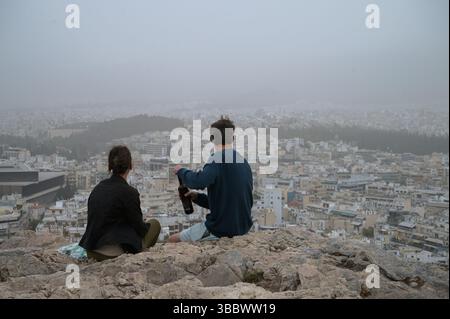 Athen, Griechenland, 16. Mai 2025. Besucher blicken über die Stadt, während Athen von Staubwolken bedeckt ist. Eine dicke Decke aus Sahara-Staub fegte am Freitag über die griechische Hauptstadt und ließ die Stadt trüben und warnte die Behörden. Quelle: Dimitris Aspiotis/Alamy Stockfoto