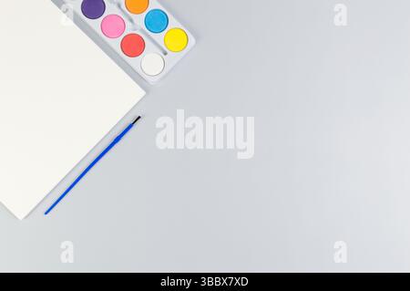 Draufsicht auf Aquarell, Papier und Pinsel auf grauem Hintergrund. Malerei, Kunst, Kopierraum, flache Lay. Stockfoto