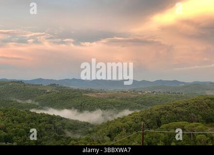 Sonnenuntergang über nebelig bewaldeten Hügeln und fernen Bergen in der ruhigen ländlichen Toskana Stockfoto