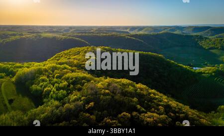 Aus der Vogelperspektive vom Apple Blossom Overlook Park mit sanften grünen Hügeln und Ackerland bei Sonnenuntergang mit goldenem Licht über die ländliche Landschaft von Wisconsin. Stockfoto