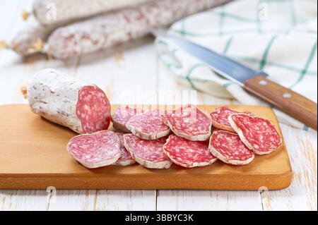 Scheiben köstlicher spanischer Wurst auf einem weißen Holztisch, selektiver Fokus. Stockfoto