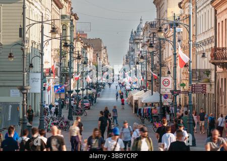 Polen, Lodz, 2. Mai 2025, polnische Flaggen geschäftiger Tag auf der Piotrkowska Straße, der Hauptpromenade in Łódź, Polen. Die Szene ist voller Fußgänger walki Stockfoto