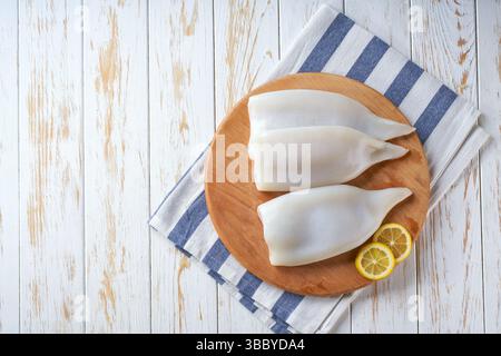 Frische, rohe Tintenfische. Tintenfischrohre auf einem Holztisch mit Kopierraum. Meeresfrüchte-Konzept. Stockfoto